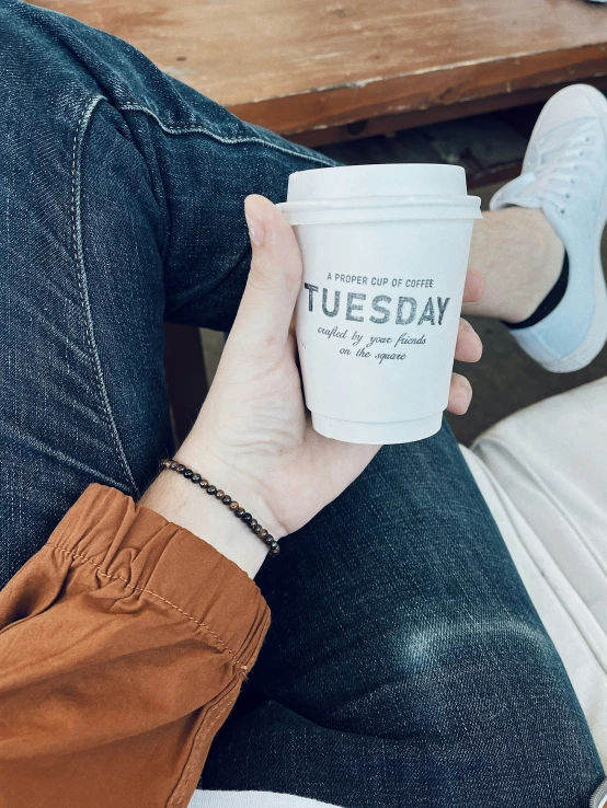 a woman holds up her coffee cup in front of her face