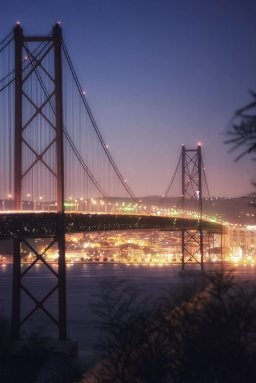 the view of a bridge and its lights over the water at night