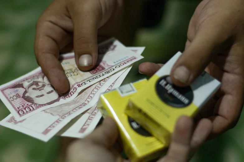 two people grabbing money off of a yellow item