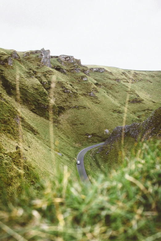 a po of a hilly road surrounded by green grass