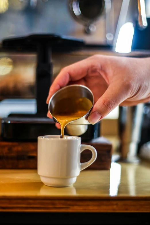 a person pouring some kind of liquid from a teacup