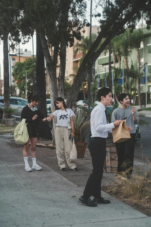 four people are standing on the sidewalk near the street