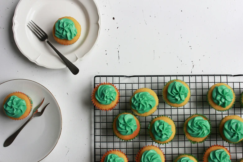 cupcakes decorated with blue and green frosting are on a wire rack