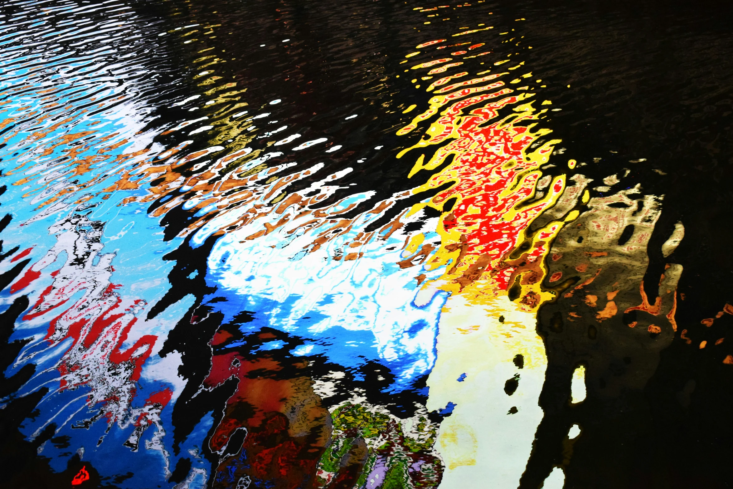 many different colored reflections on water in front of a brick wall