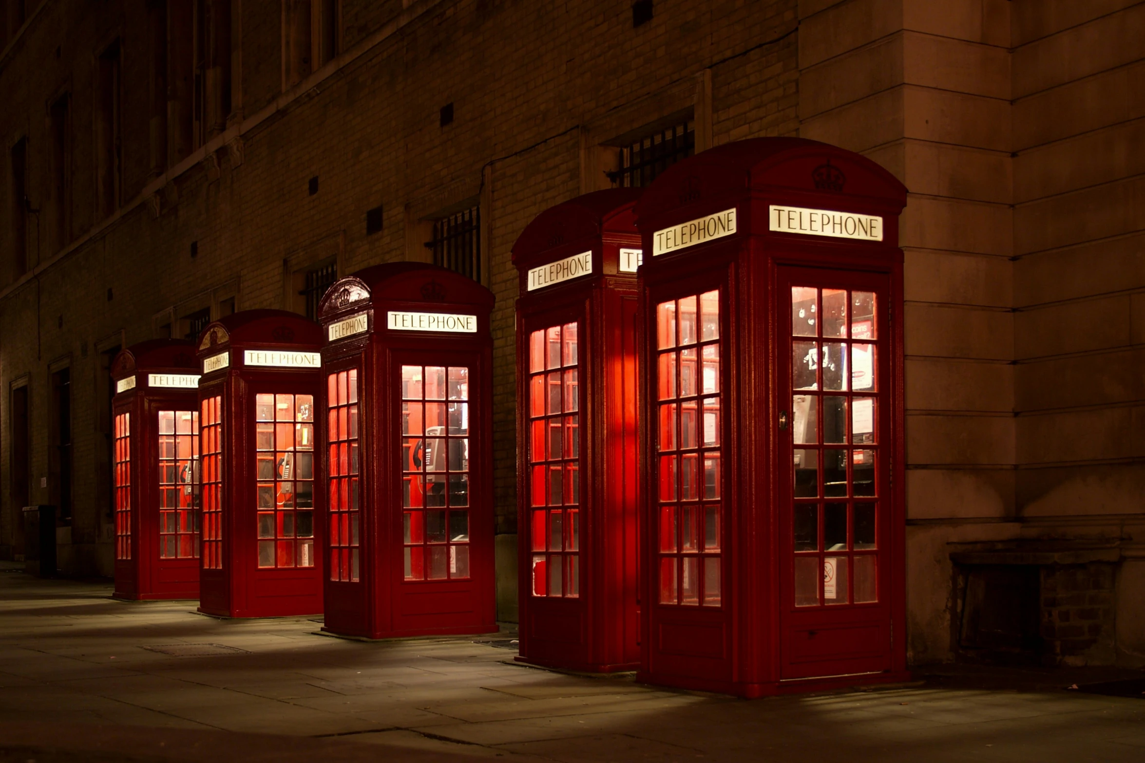 a row of red telephone booths stand in the middle of a building