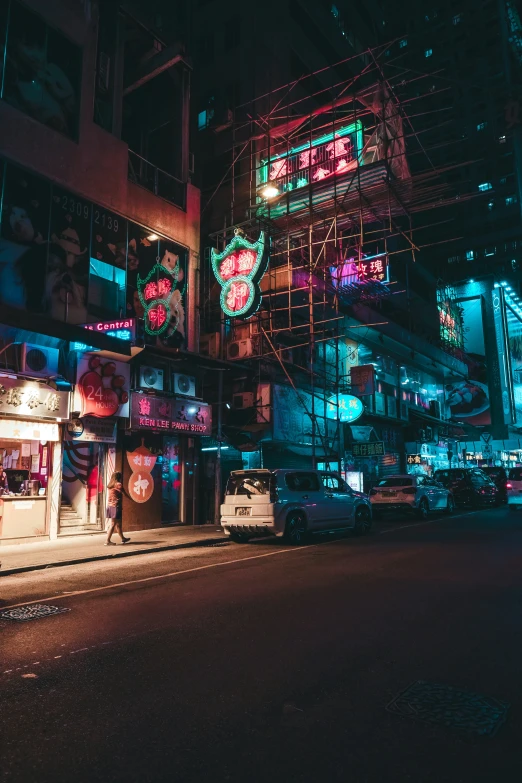 a building with neon signs and scaffolding along it