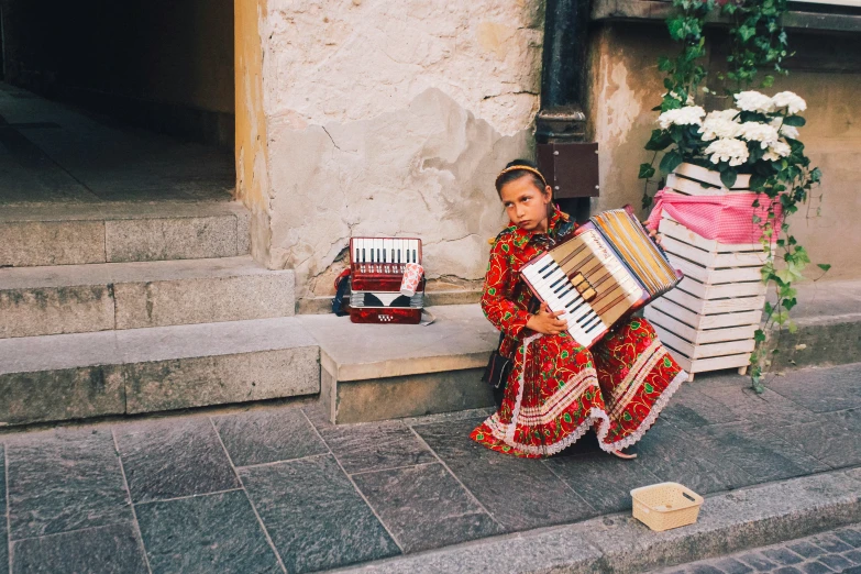 a woman in a bright colored dress sitting with a large accordion