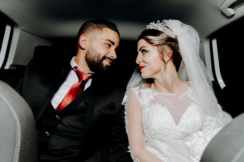 a bride and groom in the back of a car