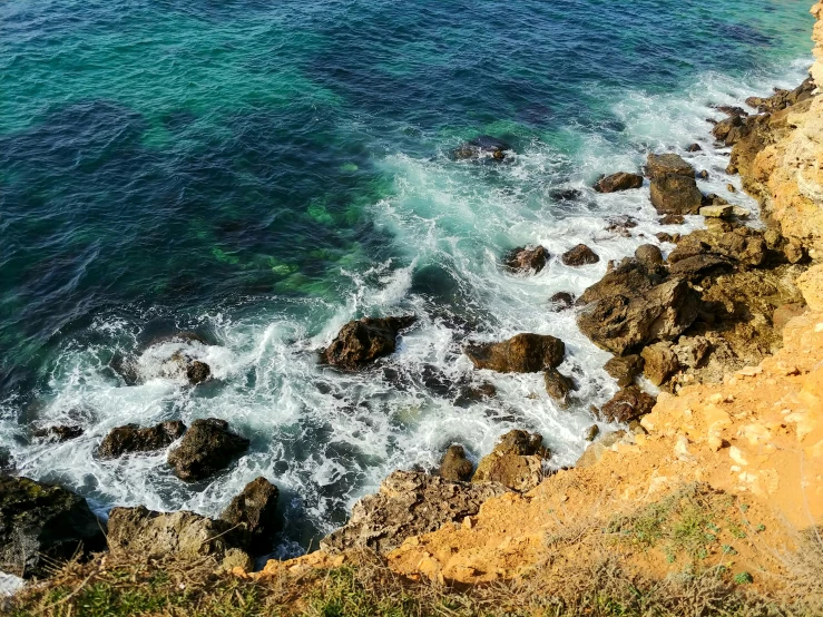 water waves and rocks are coming out of the shore