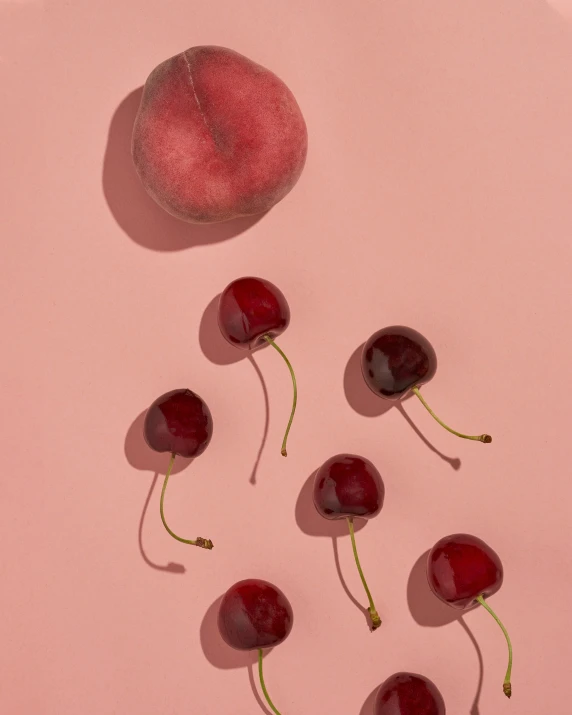 some cherries are laying next to each other on a pink background