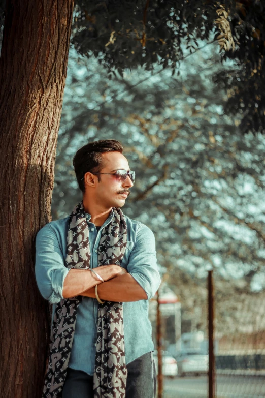 a man standing under a tree near a fence