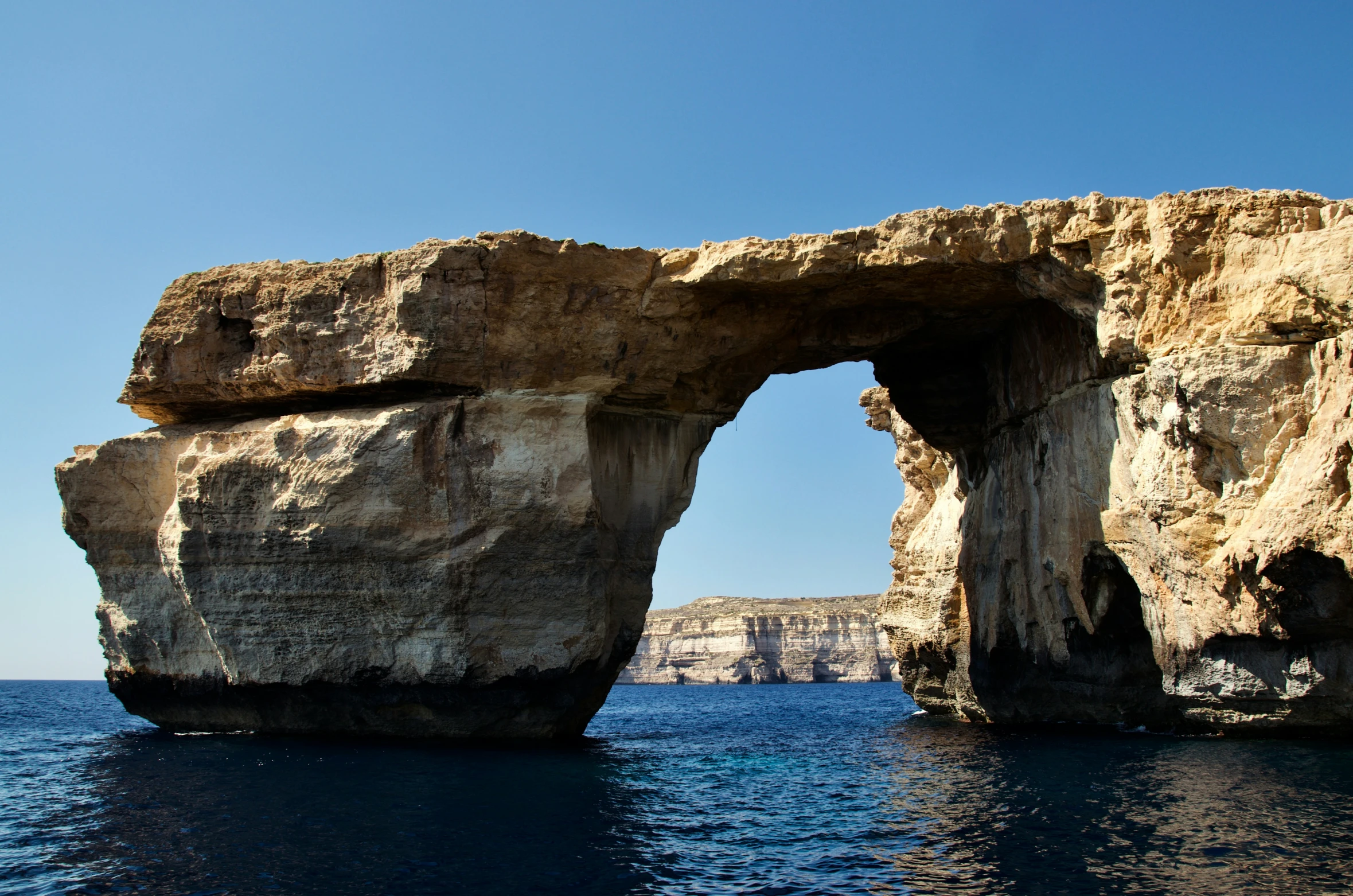 a stone arch on the coast next to an ocean