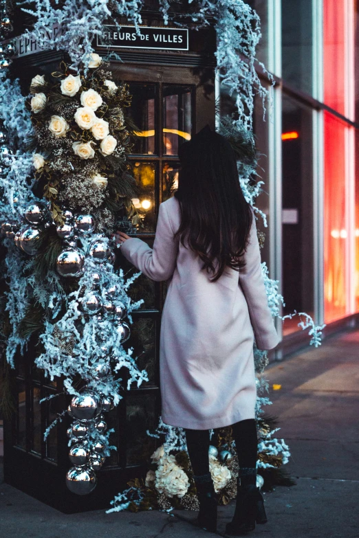 a girl wearing winter boots and looking through a christmas decoration