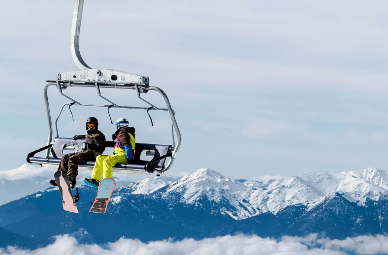 two people are sitting on the ski lift in the clouds