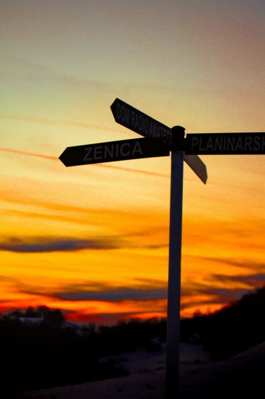 a close up of a street sign with a sunset in the background