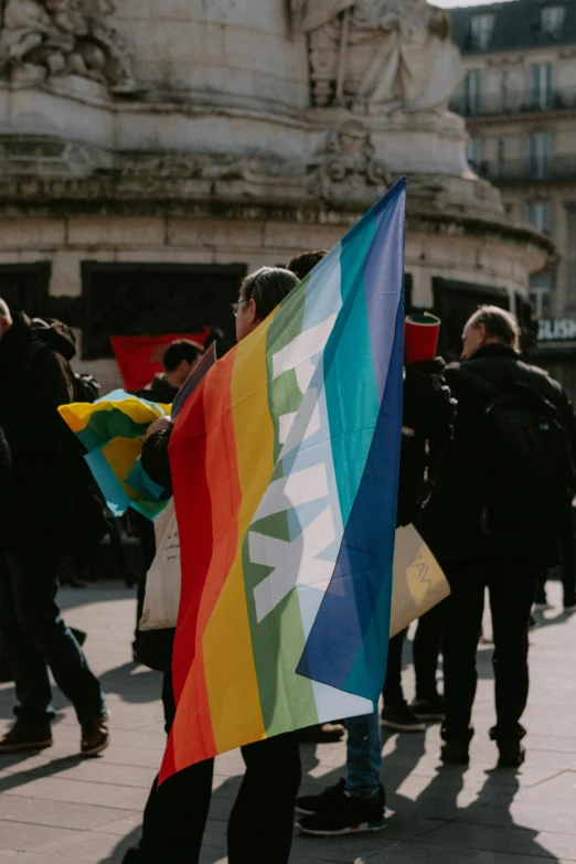 people standing on the sidewalk carrying colorful flags