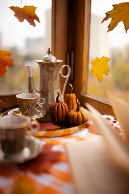 a window sill with coffee and fall leaves coming from it