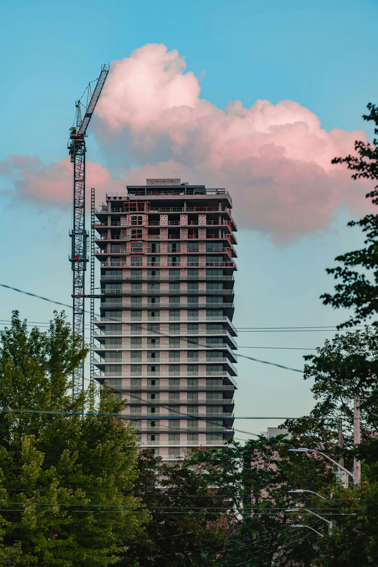 the top part of the building is tall and the base of a crane is visible on the sky