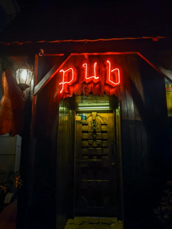 a lighted up pub sign and its entrance