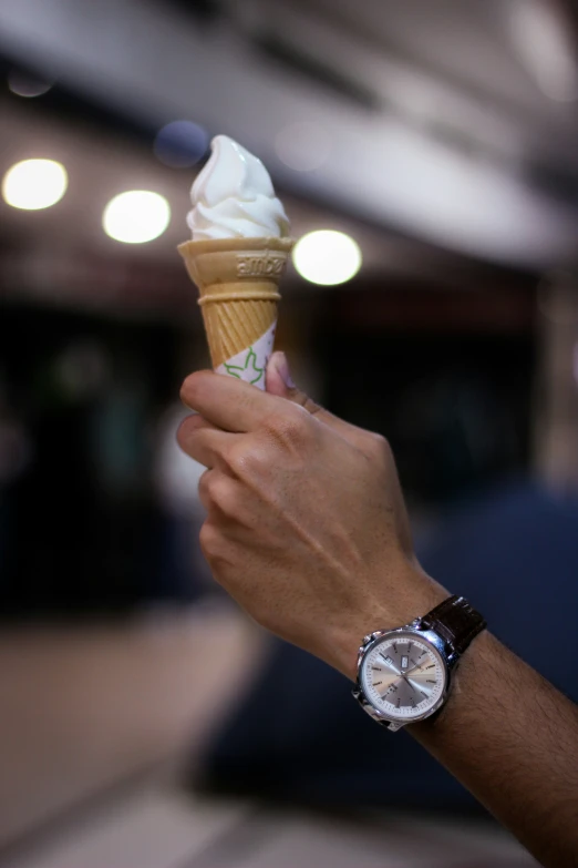 a person holding an ice cream cone with whipped cream