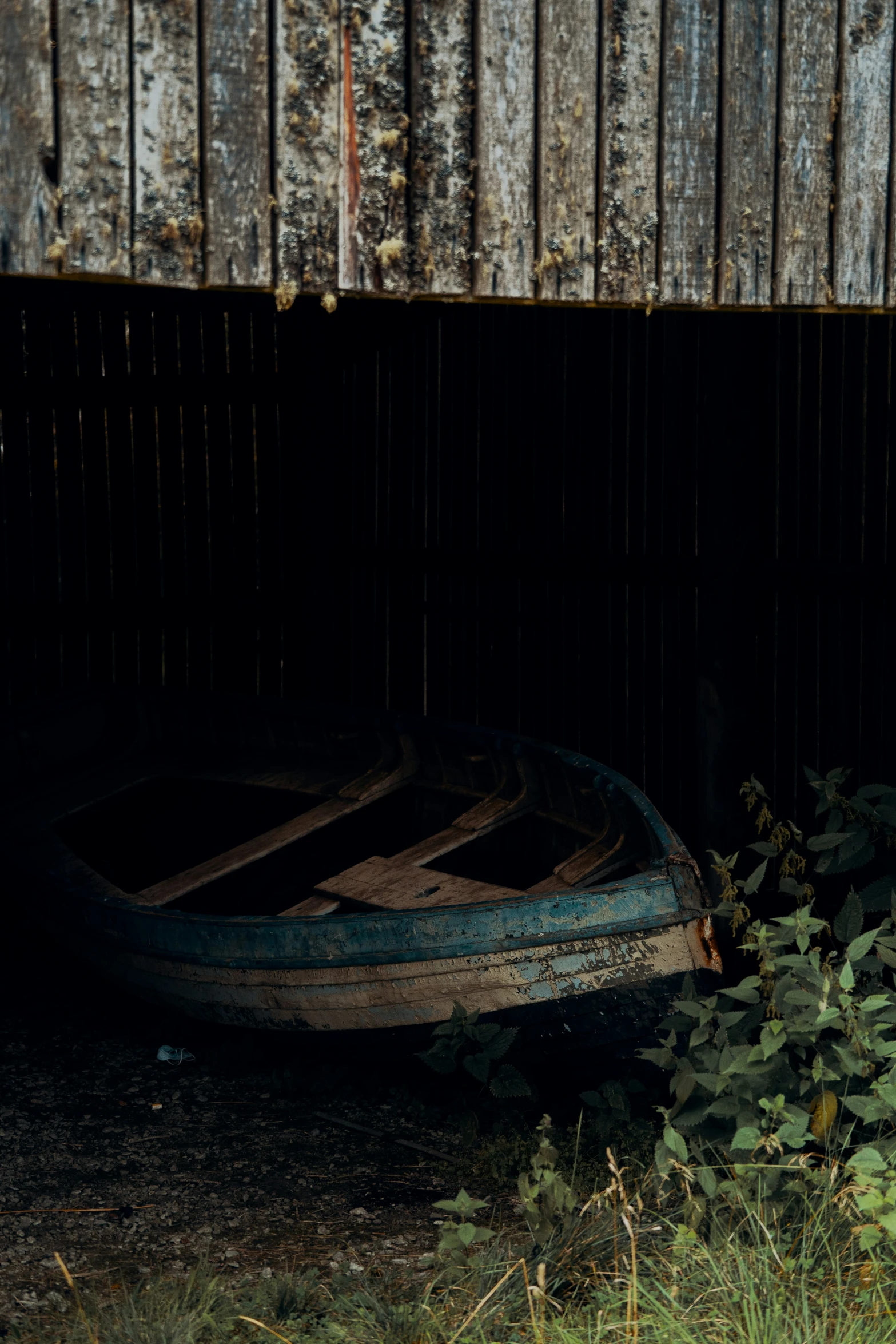 a boat in a grass yard near a wood panel wall