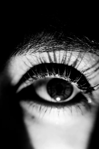 an eye with long lashes seen through a dark hole