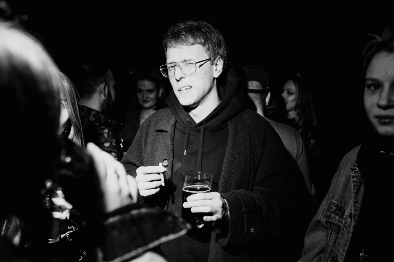 man in a crowded room holding a glass