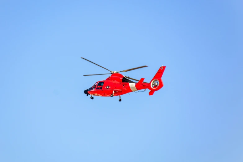 red helicopter flying in blue sky next to other aircraft