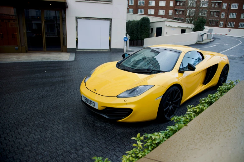 a yellow sports car parked in front of a building