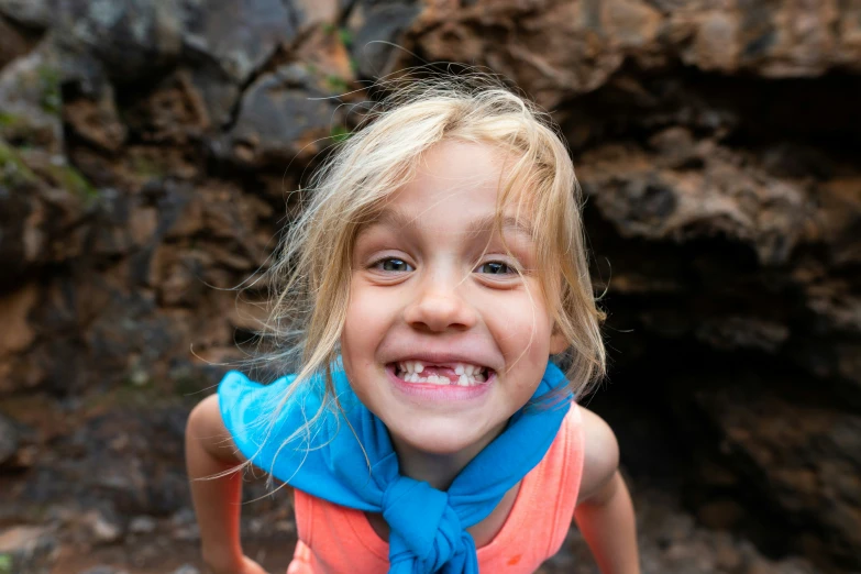 a child is smiling and holding on to a blue neck scarf