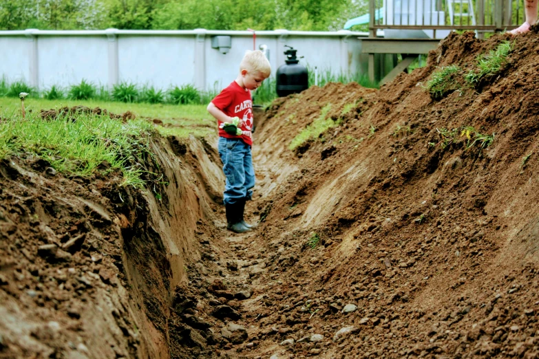 a little boy that is standing in some dirt