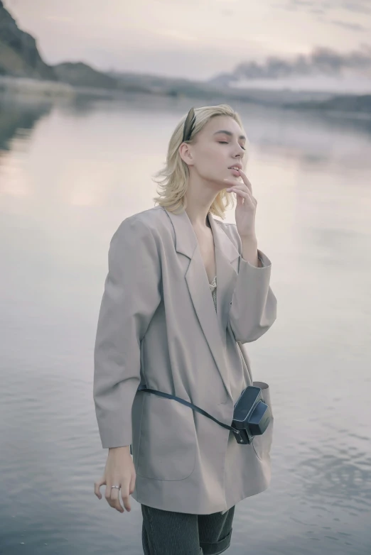 a woman in gray is standing by a body of water