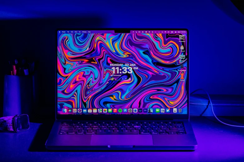 laptop with abstract colorful swirl background, lit in dark