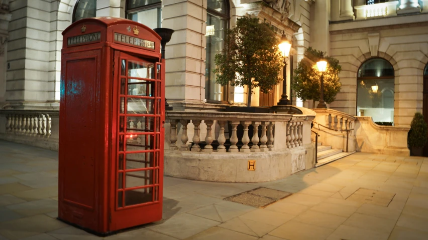 a red phone booth sits beside a railing