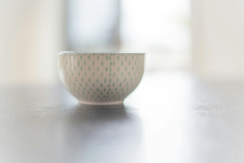 a white bowl with black spots sits on a table