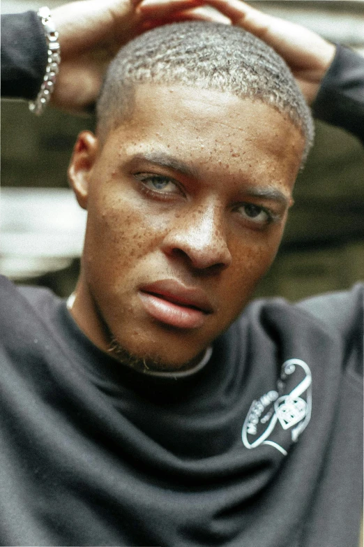 a young black man with gray hair is wearing a scarf and holding his hands up to his head