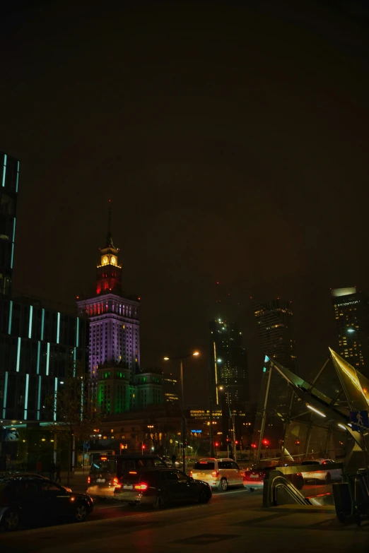 a group of cars in front of an illuminated cityscape