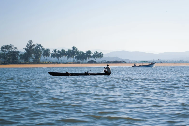 two people rowing a small boat across a river