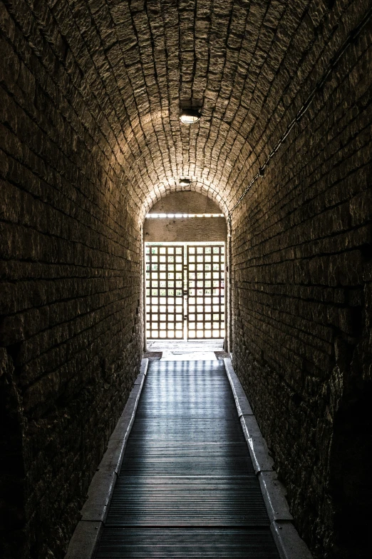 a dark tunnel with a brick ceiling and steps