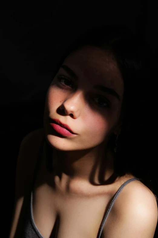 a woman with red lipstick and necklace standing in a dark room