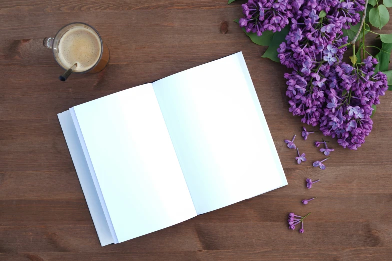 a book sitting on top of a wooden table next to a cup of coffee