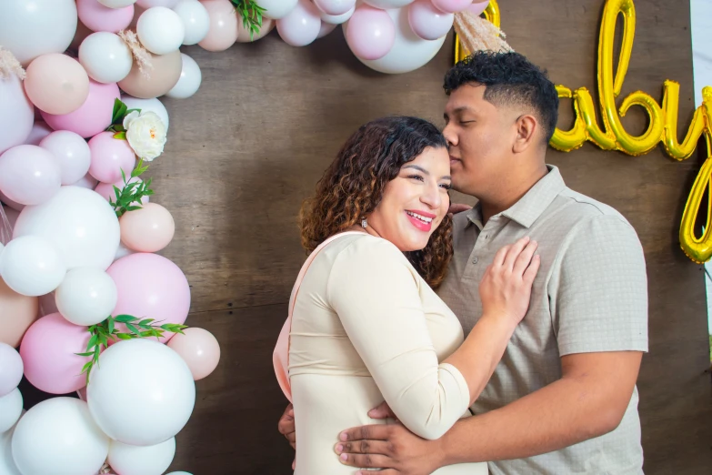 a man kissing a woman while standing in front of balloons