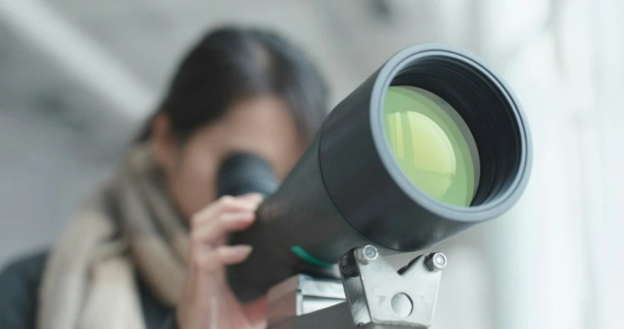 a woman looking through a telescope at soing