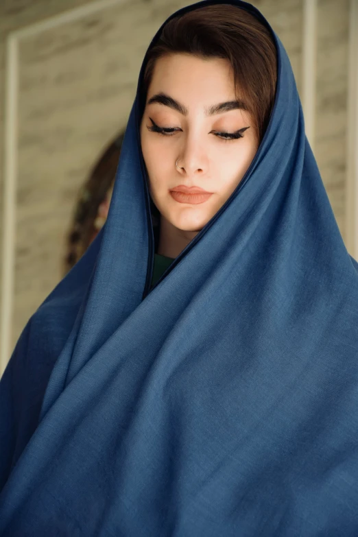 a woman wearing a blue shawl looking in the distance