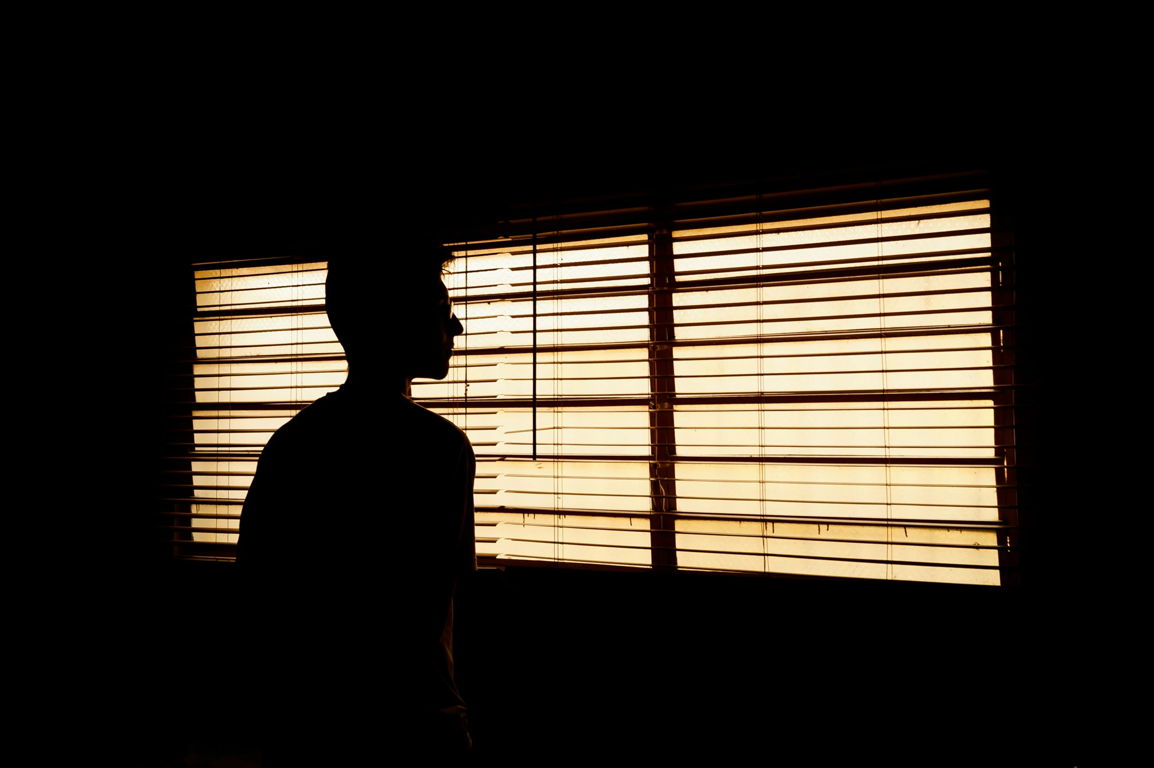 a man stands by the window in the dark