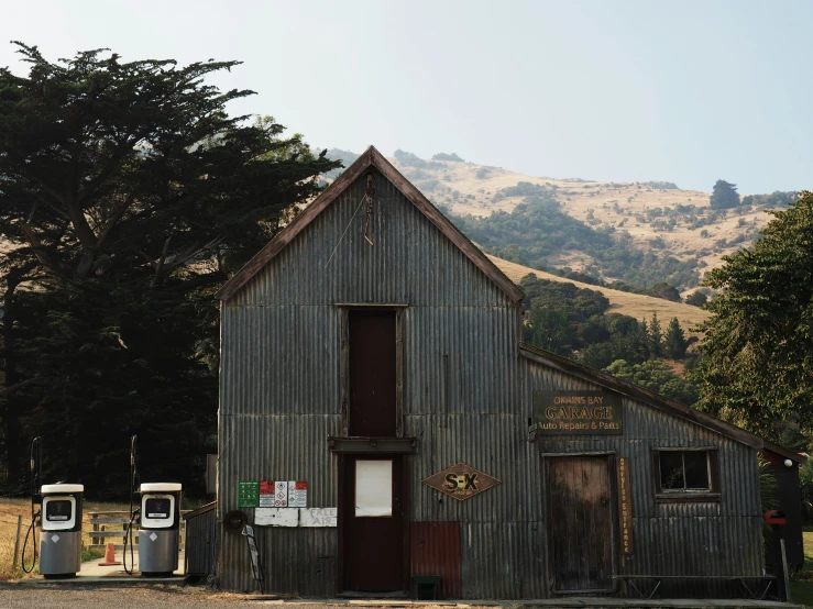 an old barn sits in the middle of a parking lot