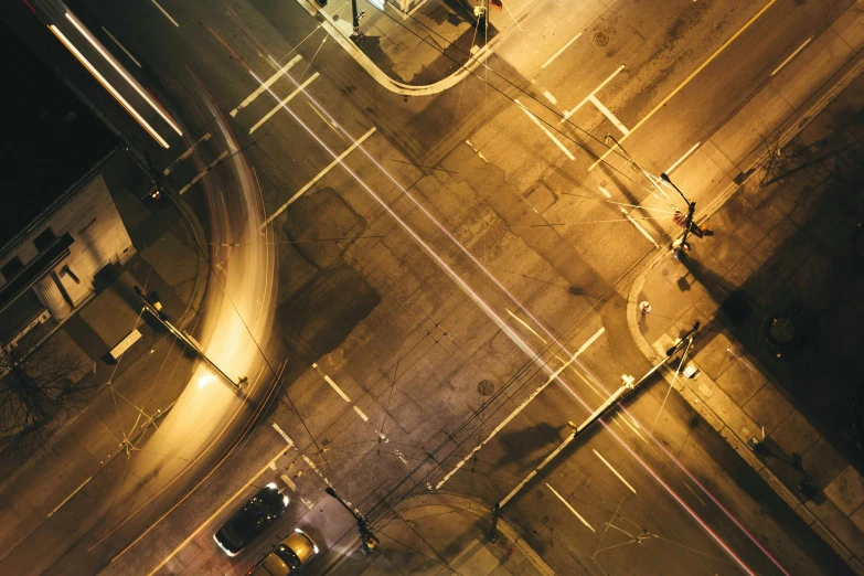 an aerial view of two cars going down a road at night