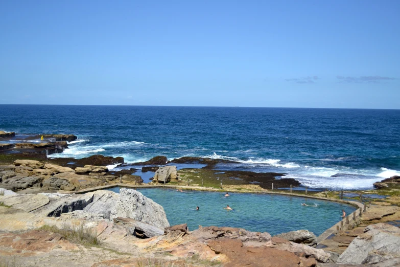 the pool at the edge of the beach is filled with clear blue water