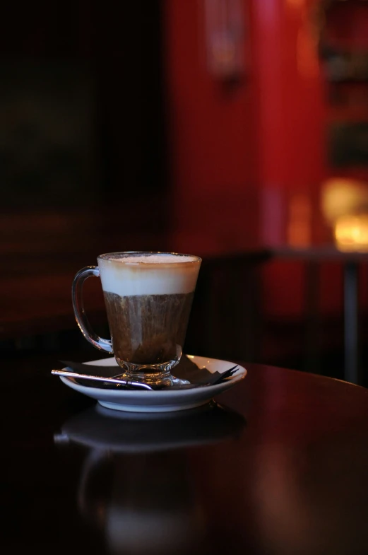 a cup with foam on the top sitting on a plate