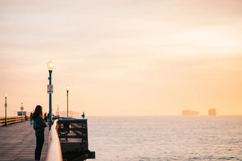 a woman standing by the water holding onto a light pole